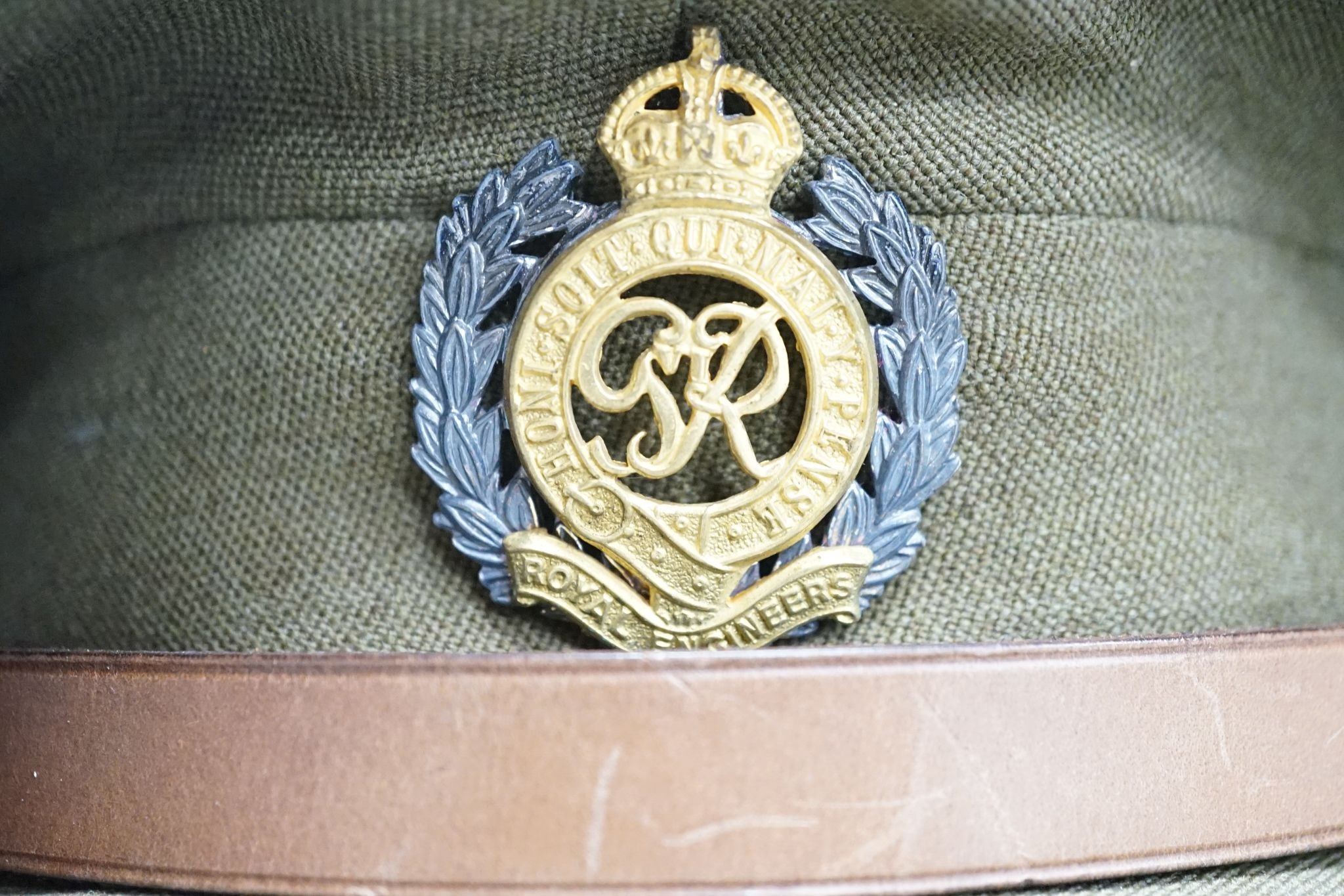 Two army officers' caps in brown leather hat box.